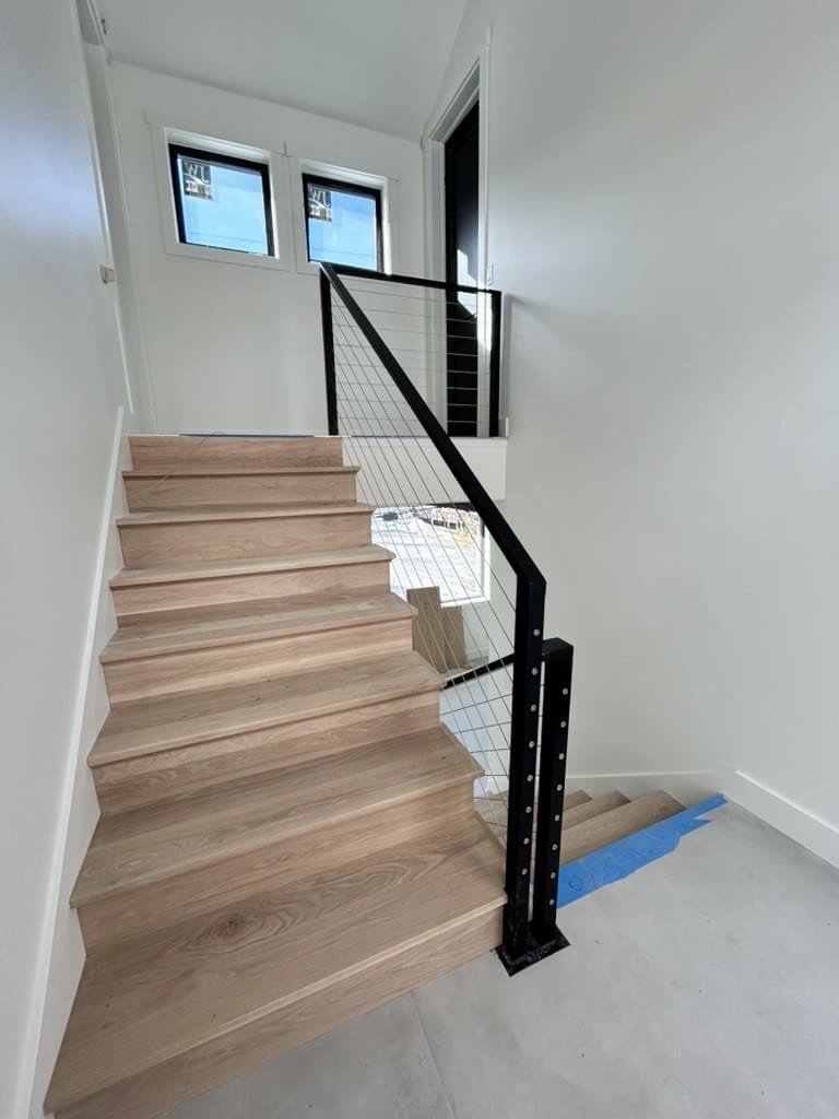 Cable railing with blackened steel posts on an interior white oak staircase
